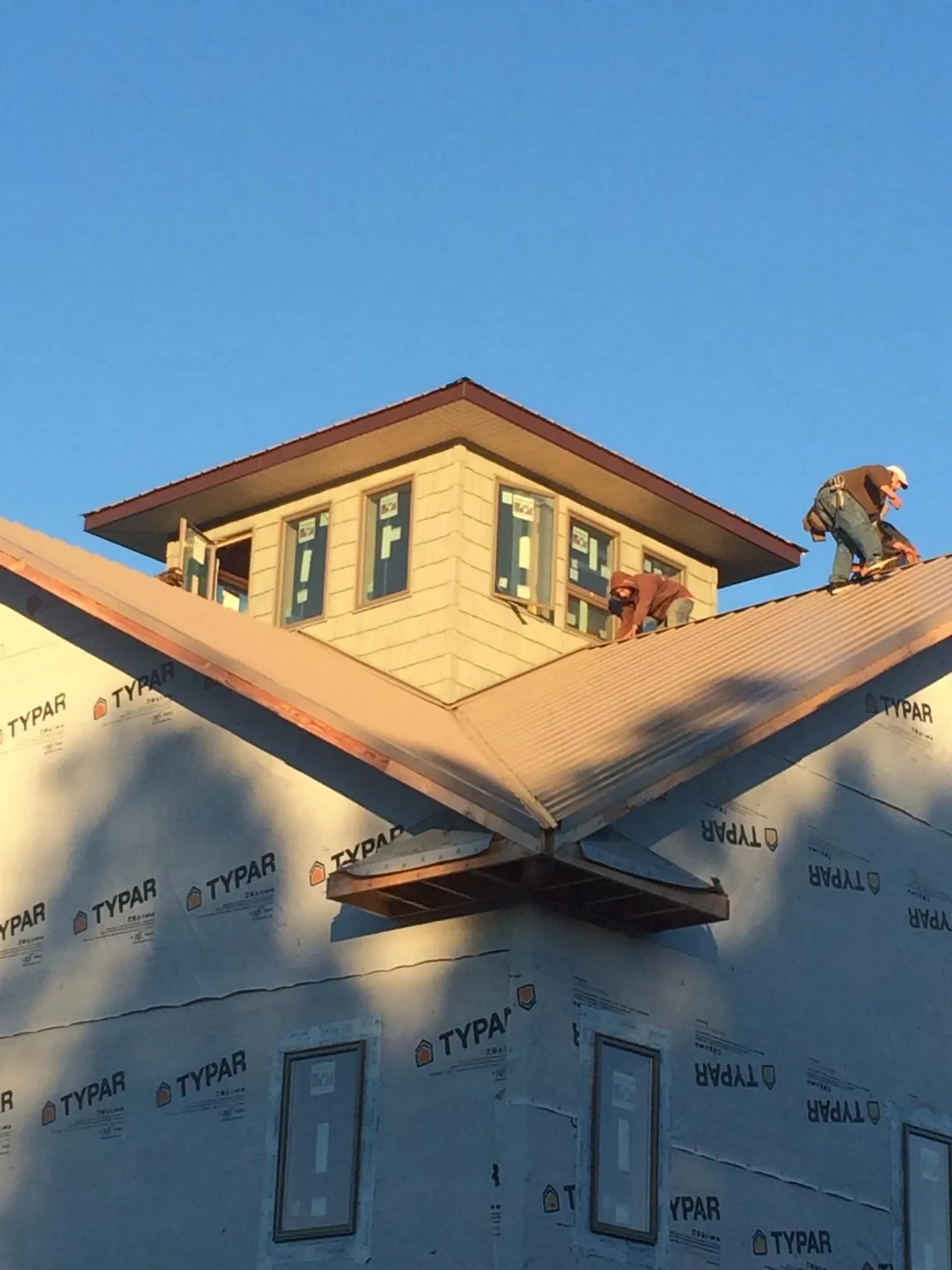Roofers working around a rooftop cupola on a new metal roof at sunset — Roof Waterproofing in Ferndale by Roofing Brothers